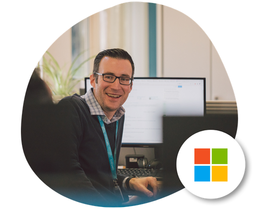A man with glasses has turned around on his desk ready to discuss Microsoft 365 Managed Services.
